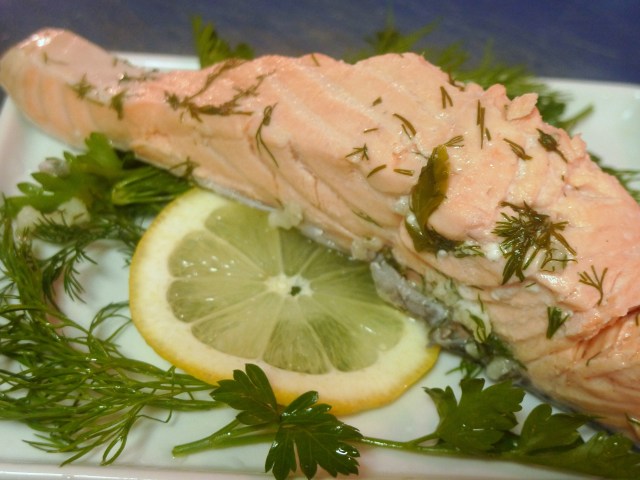 poached salmon on a bed of dill, parsley and lemon
