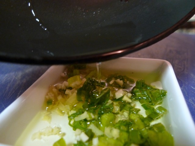 pour the hot oil over the minced garlic, ginger, and scallions